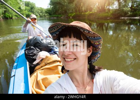 Man and woman couple, baby is sleeping, selfies are happy in family kayak trip rowing boat on the river, water hike, a summer ad Stock Photo