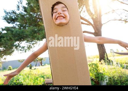 The child is funny dancing and fooling around in a box costume - round cutout for face and hands. Moving to a new house, childre Stock Photo