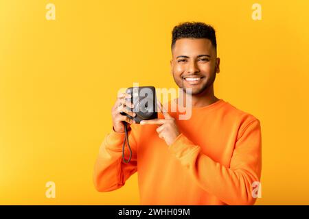 Say cheese. Studio portrait of young Indian man photographer making photo with polaroid camera. Handsome cheerful arab guy with instant photo camera looking at you Stock Photo