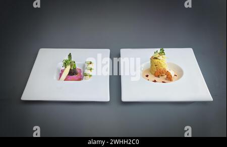 Two dishes of a modern gourmet menu, asparagus in nori leaf with beetroot sauce, fish course from saffron risotto with prawn and Stock Photo