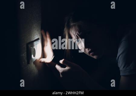 Woman young holding hand flashlight in darkness. Disconnecting home electricity off and changing electrical switch off Stock Photo