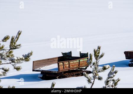 old tractor metal trailer with tracks on field in white snow. Stock Photo
