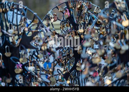 Jelgava, Latvia - January. 14. 2023:  Many heart-shaped padlocks on metal grates in the park. Concepts of wedding tradition or romance. Stock Photo