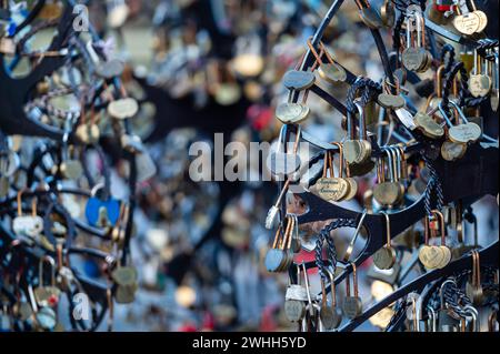 Jelgava, Latvia - January. 14. 2023:  Many heart-shaped padlocks on metal grates in the park. Concepts of wedding tradition or romance. Stock Photo