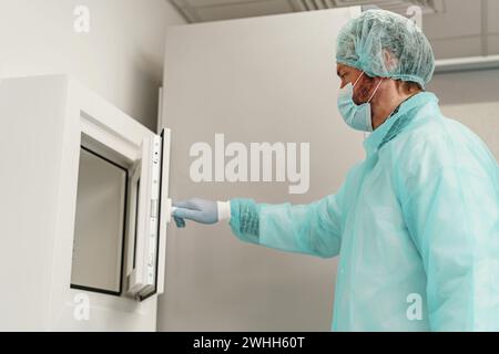 Male scientist in uniform and mask working in medical research laboratory Stock Photo