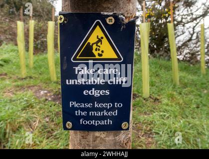 Sign warning of unstable cliff edges, keep to marked footpaths. On the South West Coastal Path above unstable cliffs at Salcombe Hill, Salcombe Regis Stock Photo