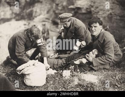 25 July 1922  “Injured soldier being cared for by the Red Cross on the South Western Front during the Irish Civil War”!  The wounded man appears to be in considerable pain and is being held and comforted.  makeshift Red Cross armbands on the two medics, and the old-fashioned kit bag seemingly holding their first aid supplies! Stock Photo