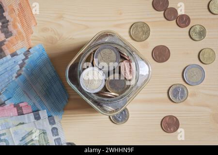 Retirement savings in euros, coins in a jar and paper currency banknotes on the desk, top view Stock Photo