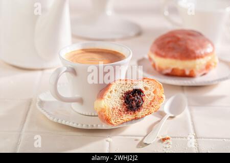 Sweet and hot doughnuts served with coffee. Donuts with plum jam and glaze. Stock Photo