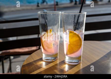 Refreshing drinks with orange slices in two glasses on a table in a seaside street cafÃ© on a sunny day, copy space, selected fo Stock Photo