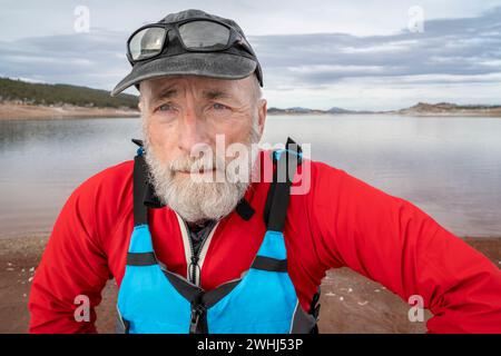 senior male paddler wearing life jacket with a wooden canoe paddle on a ...