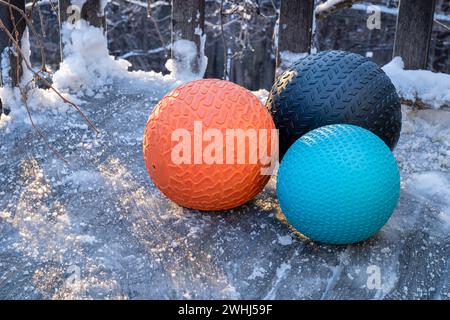 heavy slam balls filled with sand on an icy backyard deck, exercise and functional fitness concept Stock Photo