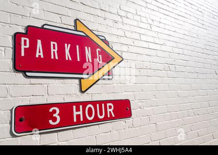 Bright red and yellow 3-Hour parking signs on white-painted brick wall. Stock Photo