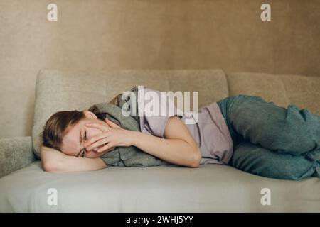 Young woman wearing scarf has flu ill sick disease cold at home indoor. Stock Photo