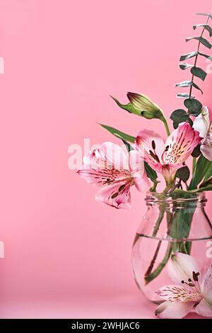 Bouquet of beautiful flowers in glass bottles on pink background. Minimal Floral Festive Decoration, copy space Stock Photo