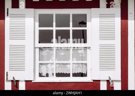 Vintage window with white shutters on a typical red and white striped wall, Costa Nova, Aveiro, Portugal Stock Photo
