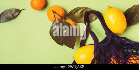 Set of citrus in mesh textile bag on green background Stock Photo