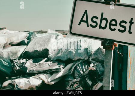 German word Asbest on a information sign. waste of asbestos on dump site. Ecology background or text Stock Photo