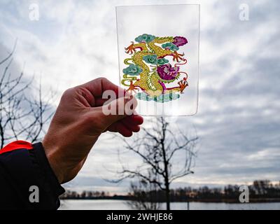 Nijmegen, Netherlands. 10th Feb, 2024. A person is seen holding a draw of a traditional Chinese dragon in front of a landscape. The Lunar New Year, also known as the Spring Festival marks the beginning of the year according to the traditional Chinese lunar calendar. Traditionally, the dragon is an auspicious symbol of strength and power. It is also associated with good fortune, wisdom, success, protection, and masculinity. (Photo by Ana Fernandez/SOPA Images/Sipa USA) Credit: Sipa USA/Alamy Live News Stock Photo