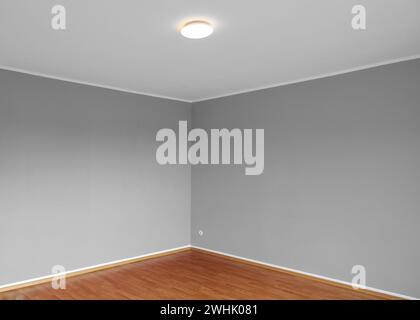 Corner of an empty living room with gray painted walls and wood parquet in an apartment, background concept for architecture, ho Stock Photo