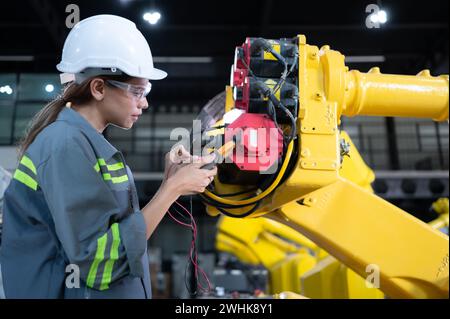 In the robots warehouse, A female engineer inspects the electrical system of every robotics arm, before delivering to the custom Stock Photo