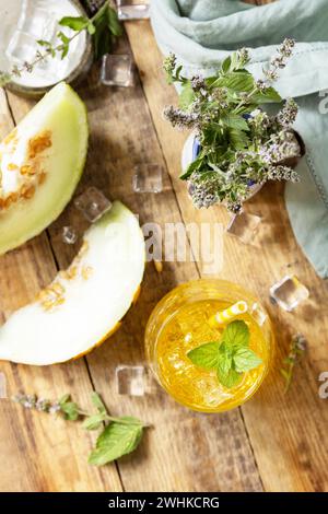 Melon lemonade in glasses with ice and mint on a wooden rustic table. Fresh refreshing fruity summer drink, seasonal beverages. Stock Photo