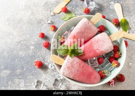 Ice cream. Summer dessert. Homemade raspberry popsicles with yogurt and raspberries on a gray stone background. Copy space. Stock Photo