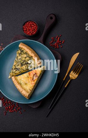 Delicious crispy quiche cut into slices with cheese, broccoli, tomatoes, salt, spices and herbs on a dark concrete background Stock Photo