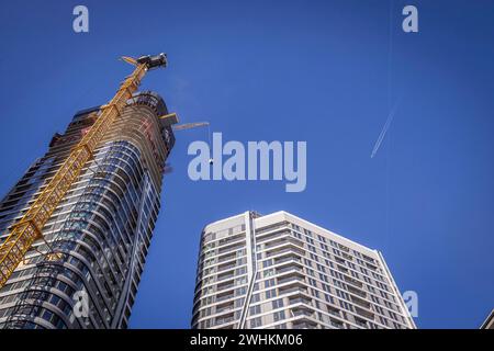 FOUR, four new tower blocks are being built here, Frankfurt 4 Tower construction site. A crane transports a portable toilet to the upper floors Stock Photo
