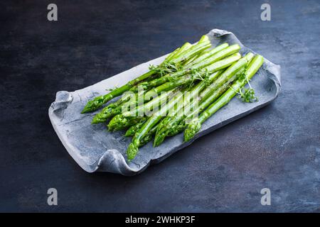 Green asparagus glazed with cress as garnish served as close-up on a design tray with text space Stock Photo