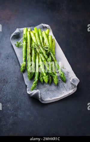 Green asparagus glazed with cress as garnish served as close-up on a design tray with text space Stock Photo