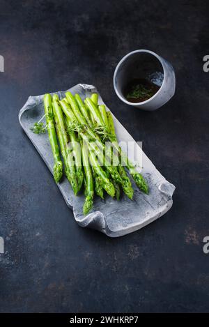 Green asparagus glazed with cress as garnish served as close-up on a design tray with text space Stock Photo