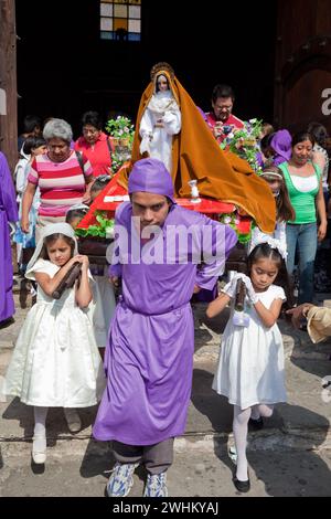 Antigua, Guatemala.  Semana Santa (Holy Week).  Young girls leaving the Cathedral of San Jose carrying an anda with the Virgin Mary. Stock Photo