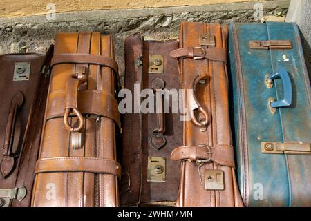 Old leather suit cases standing by a wall. Bags are used and weathered Stock Photo