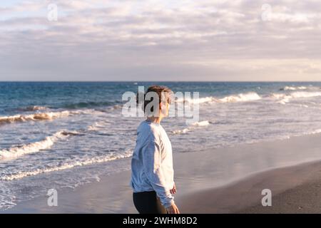 Young woman walking on the beach at sunset Stock Photo