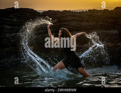 Middle-aged woman dancing and throwing water in the air Stock Photo