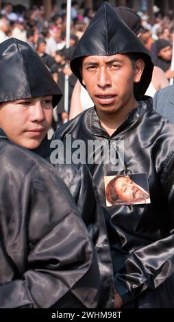 Antigua, Guatemala.  Cucuruchos in black accompany a Good Friday float in a religious procession during Holy Week, La Semana Santa. Stock Photo