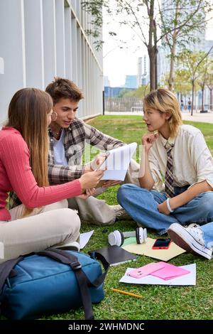 Group of young international university students sitting on the grass outside the faculty building Stock Photo