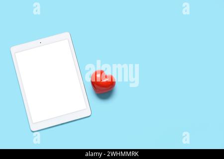 Tablet computer with red heart on blue background. Concept of online dating Stock Photo
