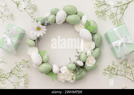 Easter wreath with sprigs of gypsophila and gifts on light background Stock Photo