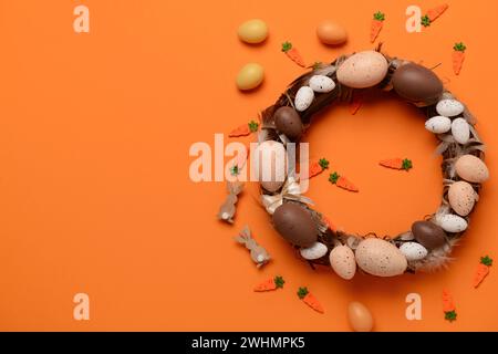 Easter wreath made of eggs and feathers on orange background Stock Photo