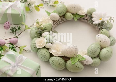 Easter wreath with white flowers, eggs and butterflies on light background Stock Photo