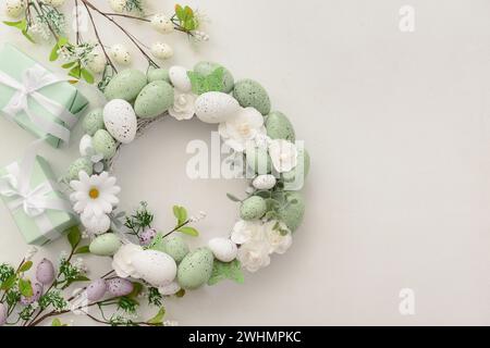 Easter wreath with white flowers, eggs and butterflies on light background Stock Photo