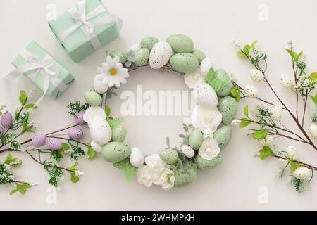 Easter wreath with white flowers, eggs and butterflies on light background Stock Photo
