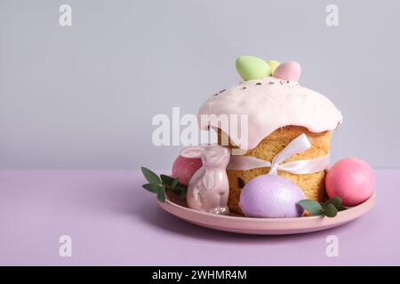 Composition with delicious Easter cake, porcelain bunny and painted eggs in plate on color background Stock Photo