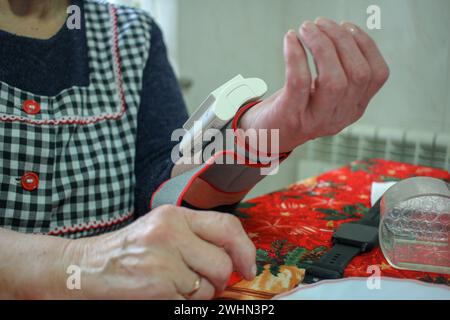 An older woman taking her blood pressure reading at home Stock Photo