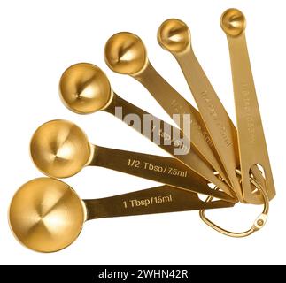 Golden metal measuring spoons for bulk and liquid products on a white isolated background, top view Stock Photo