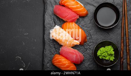 Traditional Japanese sushi with soy sauce, wasabi, chopsticks top view on dark black rustic slate. Sushi with salmon, tuna, shri Stock Photo