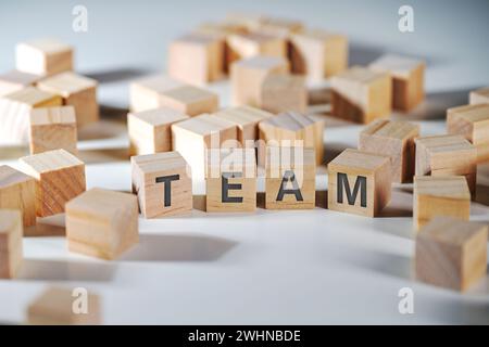 Word TEAM written on wooden cubes surrounded by a lot of blank cubes, symbol for cohesion and cooperation of the staff among com Stock Photo