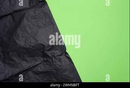 Crumpled sheet of black parchment paper, green background Stock Photo